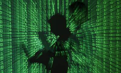 Una imagen ilustrativa muestra la proyección de código binario en un hombre que sostiene una computadora portátil en Varsovia